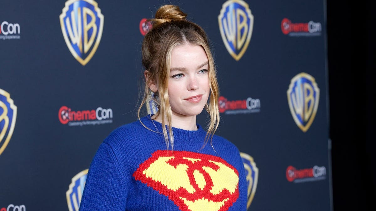 Milly Alcock standing on stage promoting the film Supergirl at CinemaCon in Las Vegas