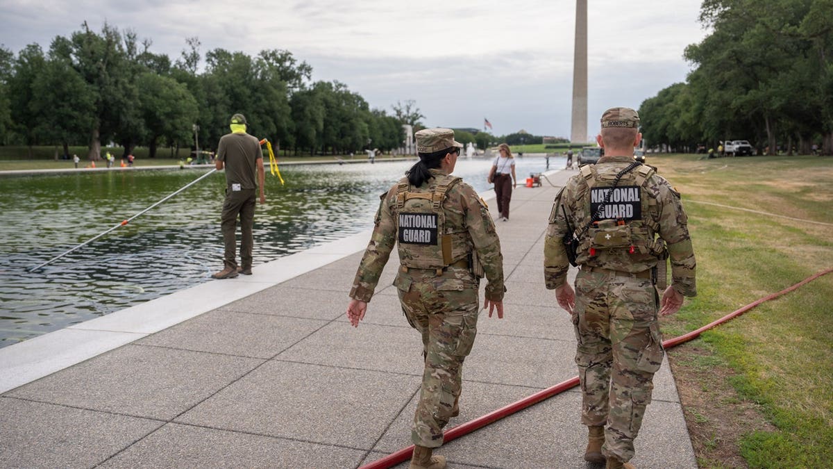 National Guard members walk past a National Park Service employee using a vacuum to clean the Lincoln Memorial Reflecting Pool, Friday, June 19, 2026, in Washington.