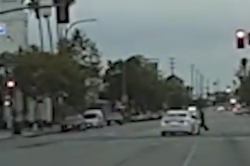 A white car swerving to hit pedestrians in the street.