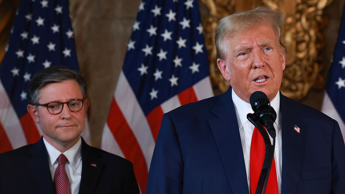 Former President Donald Trump speaking at podium with Speaker Mike Johnson standing beside him at Mar-a-Lago estate
