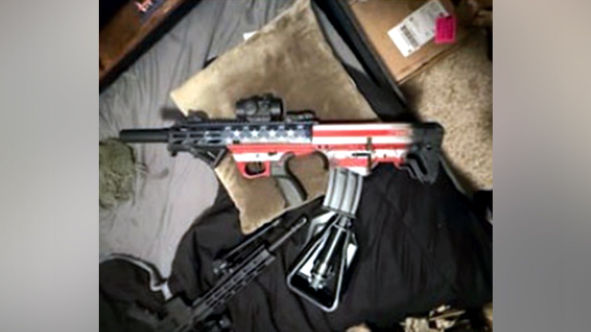Tycen Proper holding an AR-style rifle and a bullpup rifle painted with the American flag