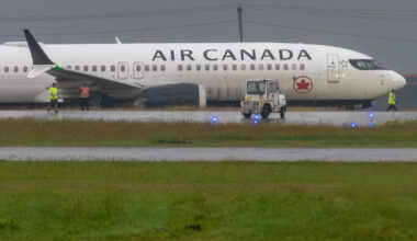 An Air Canada plane in the grass next to a taxiway.