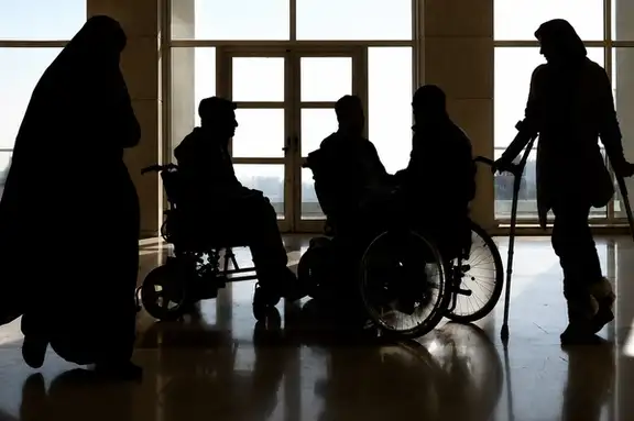 Silhouettes of people with disabilities gather inside a public building in Iran.