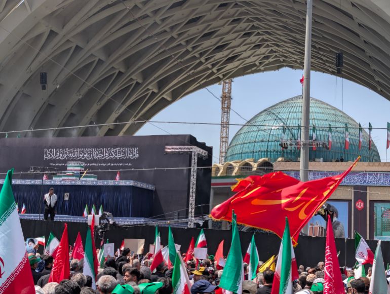 Red flags, associated with martyrdom in Shia Islam and carrying religious messages, were carried by mourners [Maziar Motamedi/Al Jazeera]