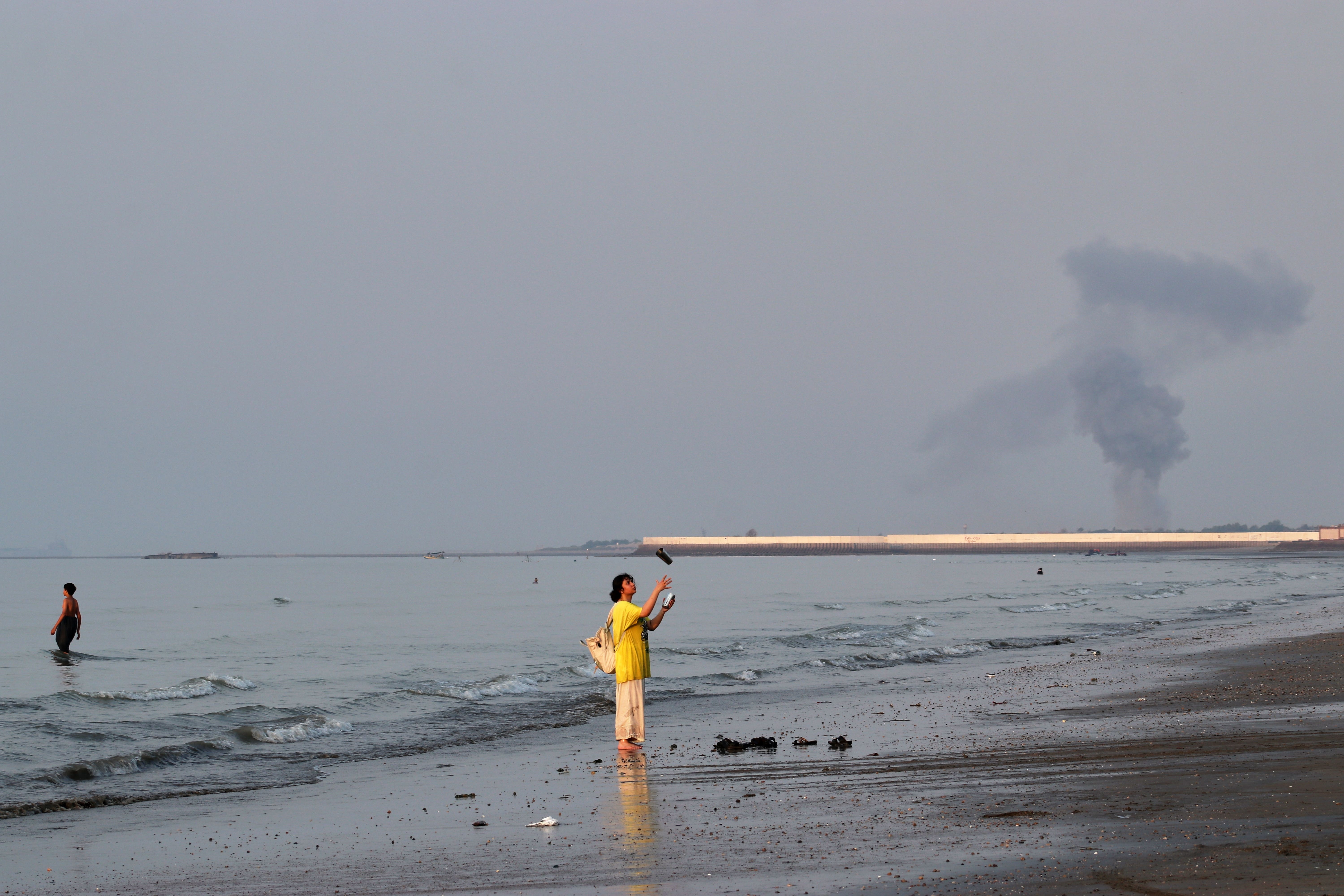 A woman stands at the water’s edge along the Strait of Hormuz, as many feel that Trump’s war with Iran is hurting their bank accounts