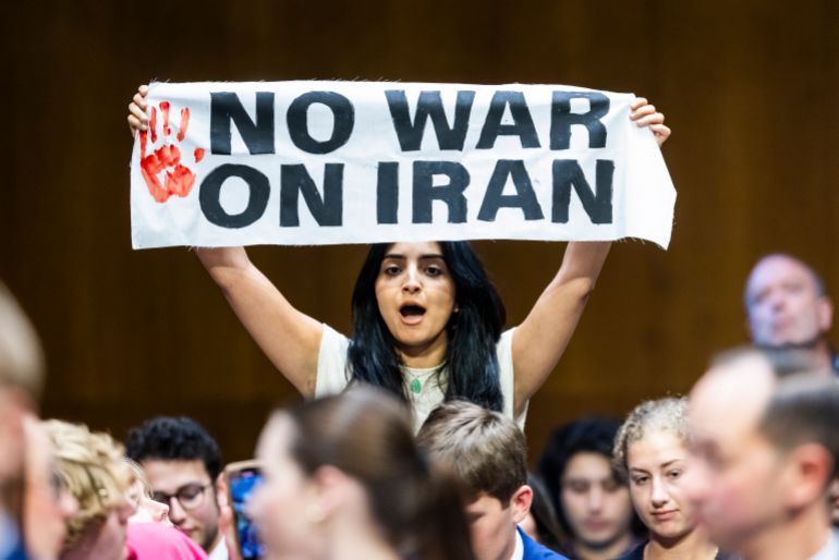 An antiwar protester holds a sign as US Secretary of Defense Pete Hegseth and Chairman of the Joint Chiefs General John Caine testify on the Defense Department’s budget before the Senate Committee on Appropriations in the Dirksen Senate Office Building in Washington, DC, on July 21, 2026