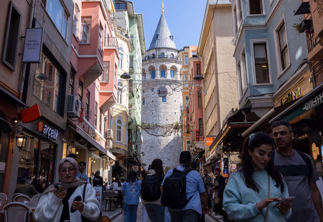 People walk on a small street that leads to the historical Galata Tower in Istanbul.