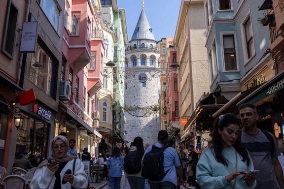 People walk on a small street that leads to the historical Galata Tower in Istanbul.