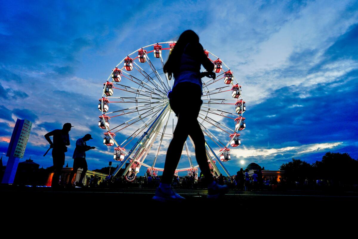 A woman is silhouetted in front of a Ferris wheel.