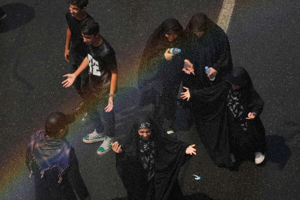 Mourners cool off under a spray of water as they walk to the Imam Khomeini Mosalla Grand Mosque during the dayslong funeral ceremonies for the late Iranian Supreme Leader Ayatollah Ali Khamenei in Tehran, Iran, Saturday, July 4, 2026. (AP Photo/Vahid Salemi)