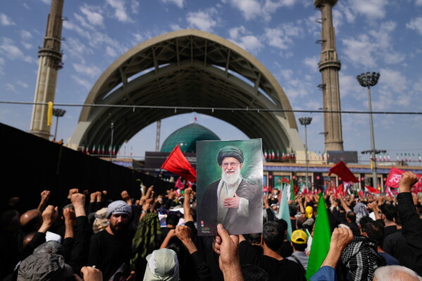 A mourner holds a portrait of the late Iranian Supreme Leader Ayatollah Ali Khamenei as mourners gather for the start of the dayslong funeral ceremonies for Khamenei and members of his family at the Imam Khomeini Mosalla Grand Mosque in Tehran, Iran, Saturday, July 4, 2026. (AP Photo/Altaf Qadri)