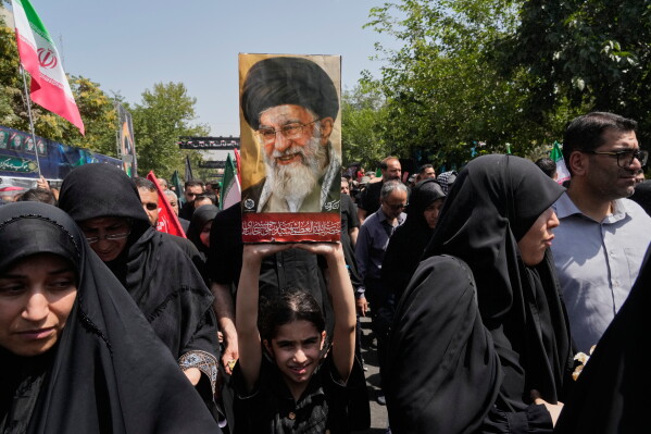 A girl holds a portrait of the late Iranian Supreme Leader Ayatollah Ali Khamenei as she walks to the Imam Khomeini Mosalla Grand Mosque during his dayslong funeral ceremonies in Tehran, Iran, Saturday, July 4, 2026. (AP Photo/Vahid Salemi)