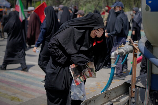 A mourner cools herself with water outside the Imam Khomeini Mosalla Grand Mosque during the funeral ceremonies for the late Iranian Supreme Leader Ayatollah Ali Khamenei and members of his family in Tehran, Iran, Saturday, July 4, 2026. (AP Photo/Altaf Qadri)
