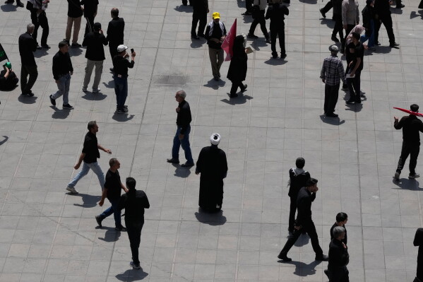 A cleric stands as mourners walk through the courtyard of the Imam Khomeini Mosalla Grand Mosque during the dayslong funeral ceremonies for the late Iranian Supreme Leader Ayatollah Ali Khamenei and members of his family in Tehran, Iran, Saturday, July 4, 2026. (AP Photo/Vahid Salemi)