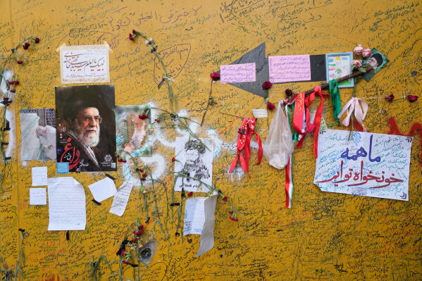 Mementoes are written on a barricade placed on the street leading to the residence of the late Iranian Supreme Leader Ayatollah Ali Khamenei where he was killed during the U.S. and Israel strike on Feb. 28, in Tehran, Iran, Saturday, July 4, 2026. (AP Photo/Vahid Salemi)