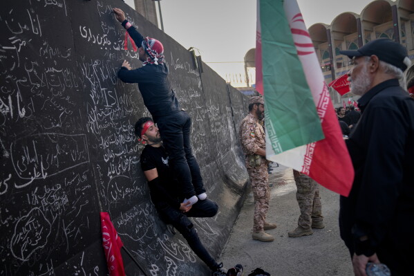 Mourners write messages on a wall during the funeral ceremonies for slain Iranian Supreme Leader Ayatollah Ali Khamenei and members of his family at the Imam Khomeini Mosalla Grand Mosque in Tehran, Iran, Saturday, July 4, 2026. (AP Photo/Altaf Qadri)