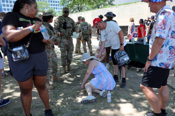 Visitors experiencing excessive heat sit on the ground at the national mall during Independence Day events honoring the nation's 250th anniversary, Saturday, July 4, 2026, in Washington. (AP Photo/Rahmat Gul)