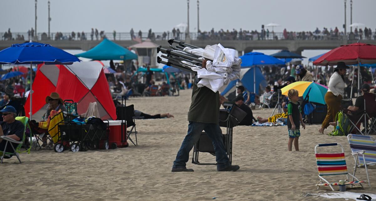 A spectator carries his pop-up tent and folding chair in Huntington Beach.