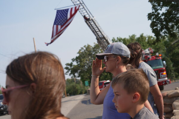 A woman salutes during a procession for firefighters who died battling wildfires near the Colorado-Utah border in Grand Junction, Colo., Monday, June 29, 2026. (AP Photo/Ty ONeil)