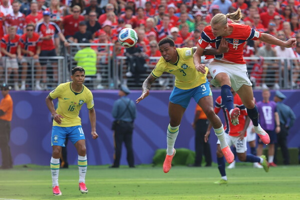 Norway's Erling Haaland (9) shoots and scores their first goal while defended by Brazil's Gabriel Magalhaes (3) during the World Cup round of 16 soccer match between Brazil and Norway in East Rutherford, N.J., near New York, Sunday, July 5, 2026. (AP Photo/Pamela Smith)