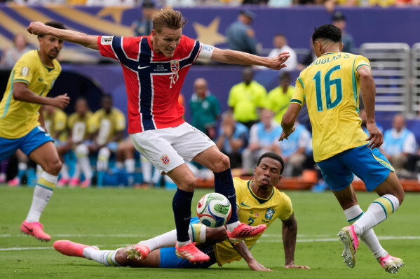 Norway's Martin Oedegaard (10) challenges for the ball with Brazil's Gabriel Magalhaes, bottom, and Douglas Santos (16) during the World Cup round of 16 soccer match between Brazil and Norway in East Rutherford, N.J., near New York, Sunday, July 5, 2026. (AP Photo/Seth Wenig)