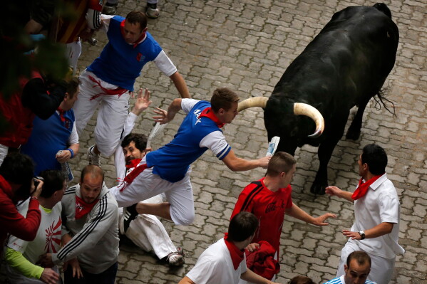 U.S. runner Bill Hillmann, 35, from Chicago, center left, falls seconds before a Victoriano del Rio ranch fighting bull gored him on his right leg during the running of the bulls of the San Fermin festival, in Pamplona, Spain, Wednesday, July 9, 2014. (AP Photo/Daniel Ochoa de Olza, File)