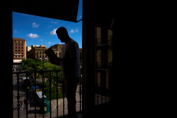 Former concierge and receptionist Fernando Hualde reads Ernest Hemingway's novel Fiesta in the Ernest Hemingway Suite at the Gran Hotel La Perla in Pamplona, northern Spain, Thursday, July 2, 2026. (AP Photo/Miguel Oses)