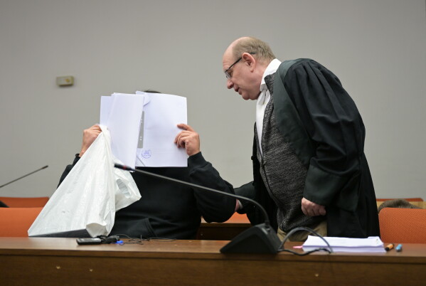 The defendant covers his face as he arrives for a trial against a network of mostly Chinese men, organized in chat groups to advise one another on how to drug and rape mostly Chinese women, in Munich, Germany, Feb. 2, 2026. (Malin Wunderlich/dpa via AP)