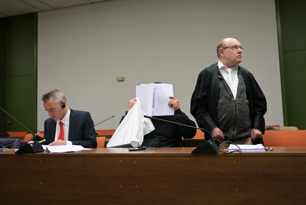 The defendant covers his face as he arrives for a trial against a network of mostly Chinese men, organized in chat groups to advise one another on how to drug and rape mostly Chinese women, in Munich, Germany, Feb. 2, 2026. (Malin Wunderlich/dpa via AP)