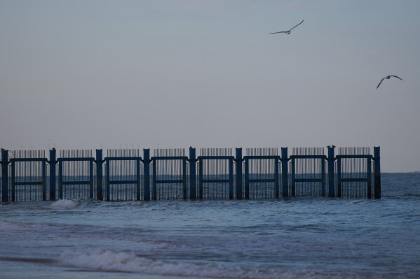 Seagulls fly past a barrier of a military firing range that had been used for decades and is slated to be cleared and opened for public use, in the Mediterranean Sea in Rishon LeZion, Israel, Saturday, Jan. 17, 2026. (AP Photo/Ariel Schalit)