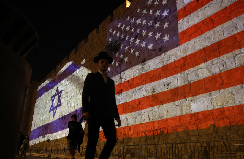 People walk past a projection depicting Israeli and US flags on the walls of Jerusalem's Old City on Oct. 22, 2025.