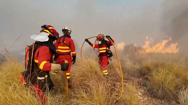 This image made from video provided by Military Emergency Unit shows members of Spain's Military Emergency Unit spraying water on burning vegetation during a wildfire near Los Gallardos, Almeria, Spain, Friday, July 10, 2026. (Military Emergency Unit via AP)