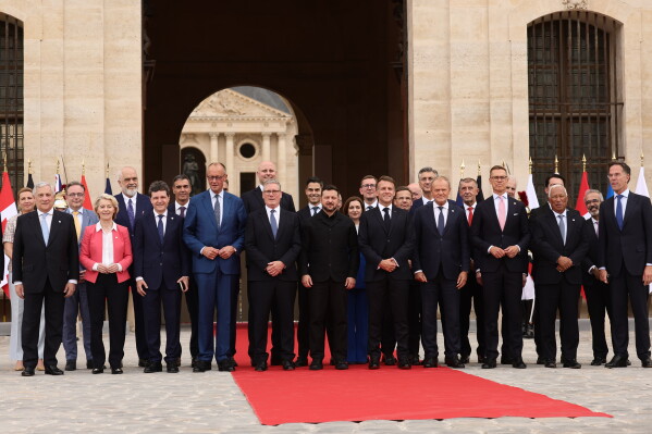 French President Emmanuel Macron and Ukrainian President Volodymyr Zelensky pose for a group photo with heads of states and governments ahead of the Coalition of the Willing summit on security guarantees for Ukraine at the Hotel des Invalides in Paris, France, Monday, July 13, 2026. (Teresa Suarez/POOL photo via AP)