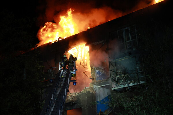 Rescue workers try to put out a fire of a residential building burning after a Russian drone attack on Zaporizhzhia, Ukraine, late Sunday, July 12, 2026. (AP Photo/Kateryna Klochko)