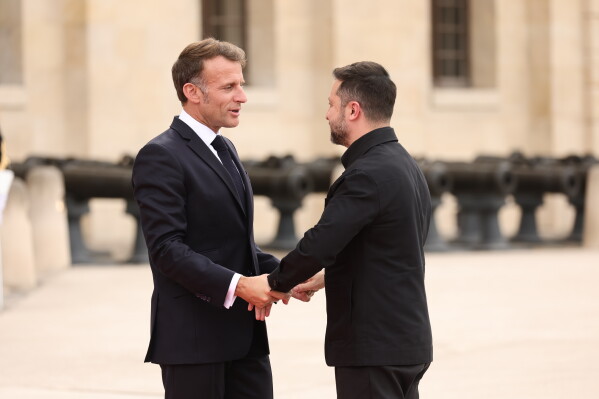French President Emmanuel Macron greets Ukrainian President Volodymyr Zelensky ahead of the Coalition of the Willing summit on security guarantees for Ukraine at the Hotel des Invalides in Paris, France, Monday, July 13, 2026. (Teresa Suarez/POOL photo via AP)