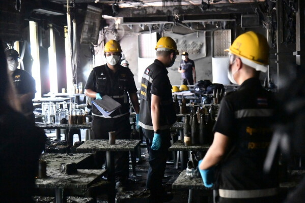 In this handout photo released by Bangkok Metropolitan Administration, forensic police officers inspect the site of a fire in Bangkok, Thailand, Monday, July 13, 2026. (Bangkok Metropolitan Administration via AP)