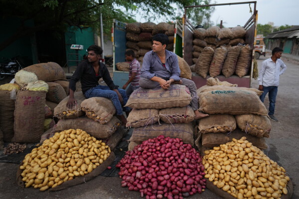 Laborers sit beside sacks of potatoes at a vegetable market in the early morning during a heat wave in Banda, northern Indian state of Utter Pradesh, Saturday, June 20, 2026. (AP Photo/Rajesh Kumar Singh)
