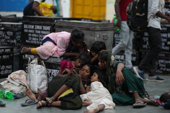 Children gather around a mobile phone as local residents rest at a railway station to escape the heat in Banda, northern Indian state of Utter Pradesh, Saturday, June 20, 2026 (AP Photo/Rajesh Kumar Singh)