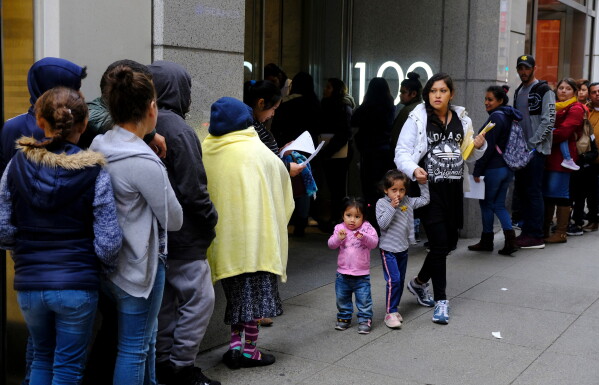 Hundreds of people stand in line outside a U.S. immigration office with numerous courtrooms in San Francisco, Jan. 31, 2019. (AP Photo/Eric Risberg, File)