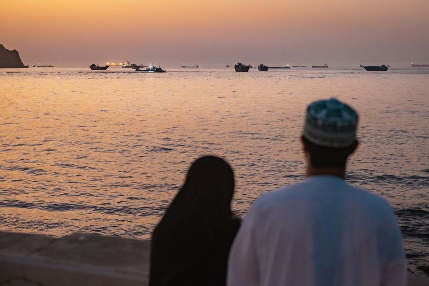 A couple in Muscat, Oman, gazes out at vessels anchored in the Strait of Hormuz on June 18.