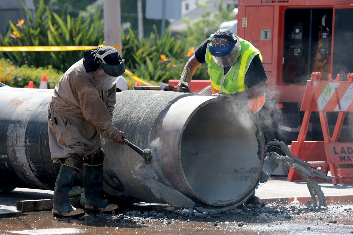 Crews prep a replacement pipe as repair work is underway