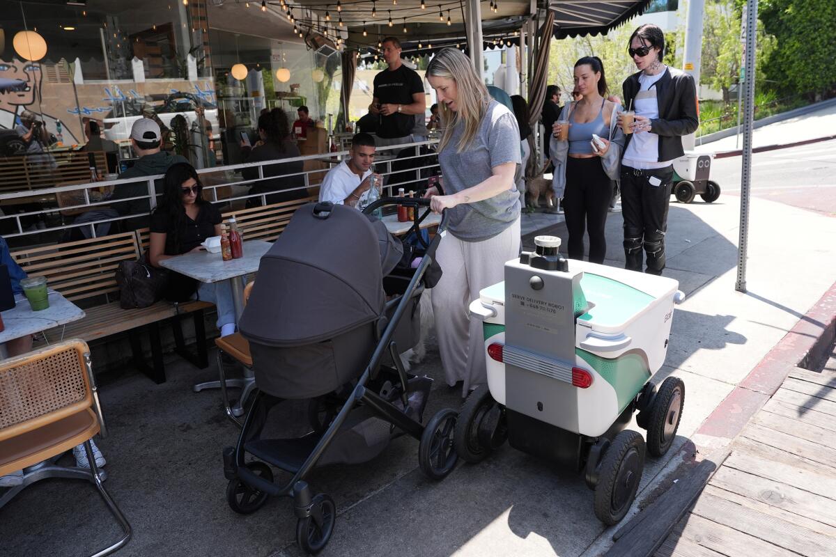 A woman pushing a child in a stroller in front of a cafe