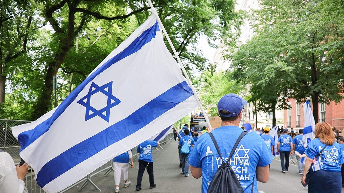 A marcher carries an Israeli flag while walking up Fifth Avenue in New York.
