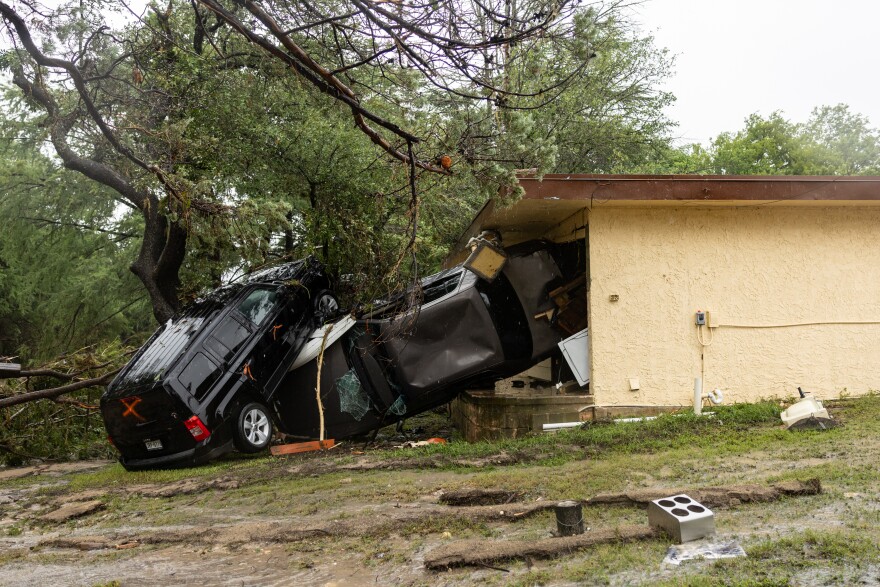 Two SUVs sit on top of each other against a small building.