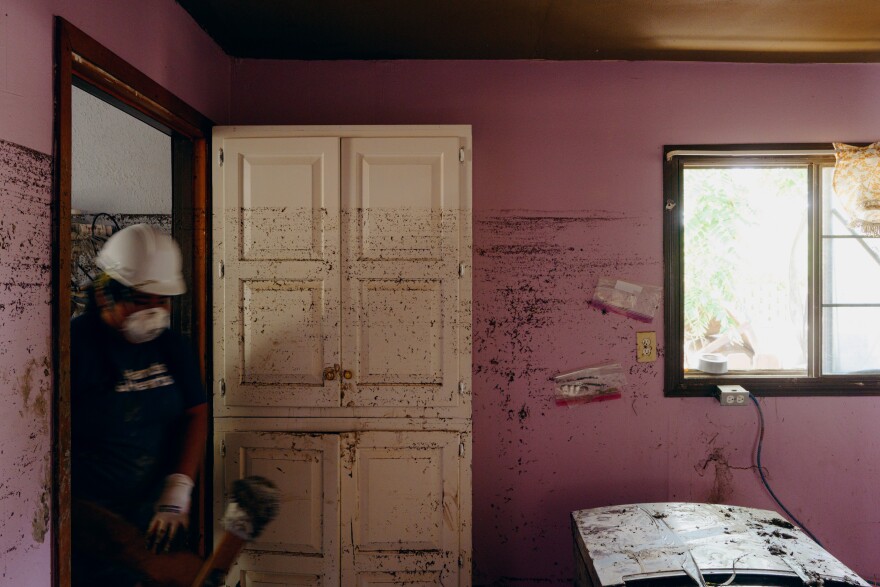 Flood waterlines can be seen inside a home as a person stands in the doorway.