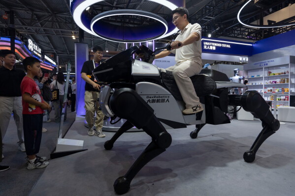 A man rides on a robot from DaxRobotics, a Chinese AI and robotics startup during the World AI Conference in Shanghai, Friday, July 17, 2026. (AP Photo/Ng Han Guan)