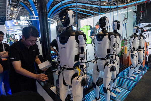 A worker stands near robots from Efort a Chinese industrial robot manufacturer during the World AI Conference in Shanghai, Friday, July 17, 2026. (AP Photo/Ng Han Guan)