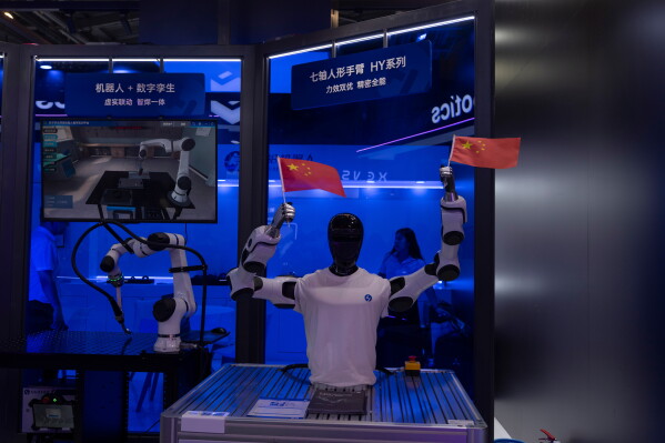 A humanoid robot from Chinese firm Huayan Robotics waves Chinese national flags during the World AI Conference in Shanghai, Saturday, July 18, 2026. (AP Photo/Ng Han Guan)