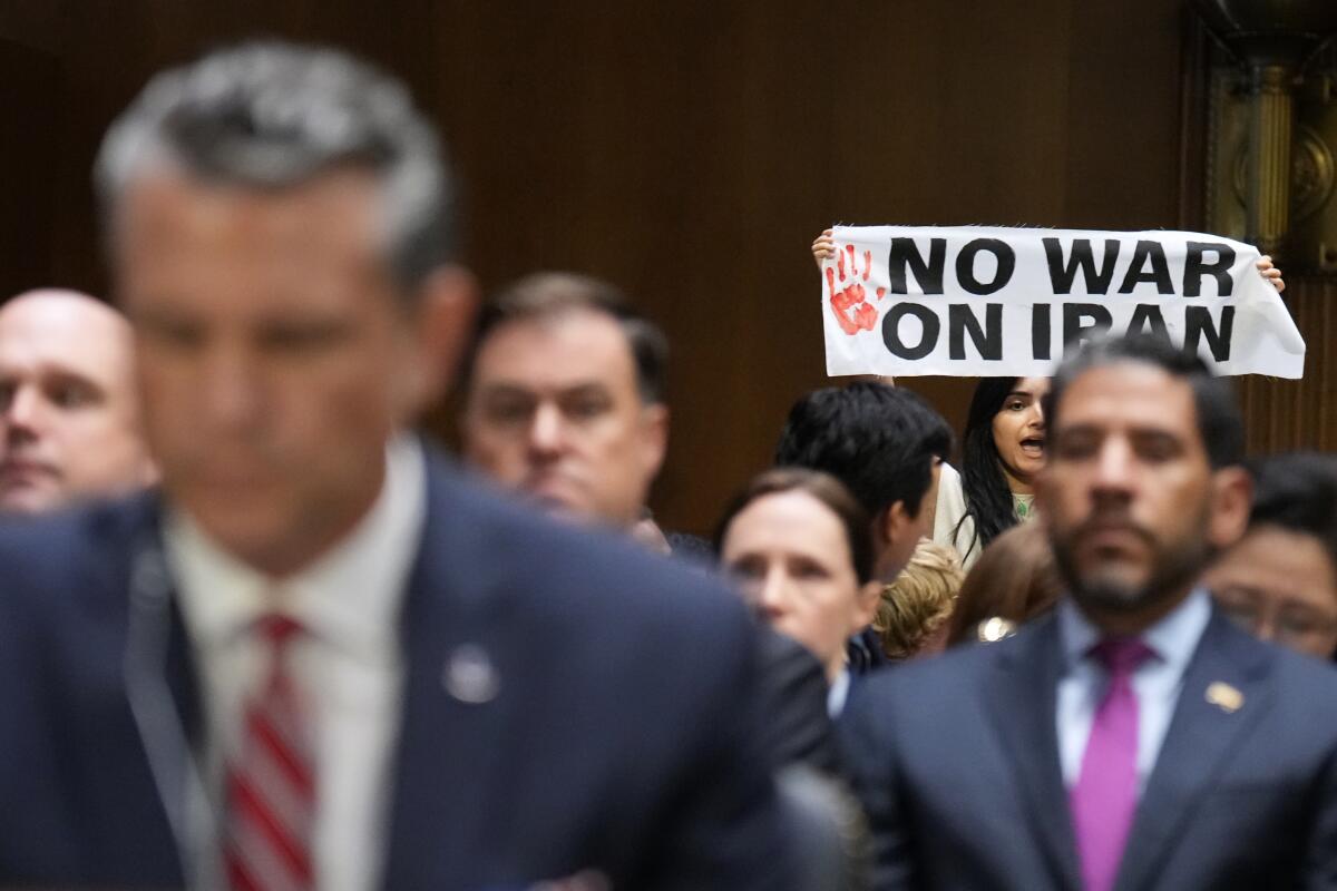 A protester holds a sign that says: No war on Iran