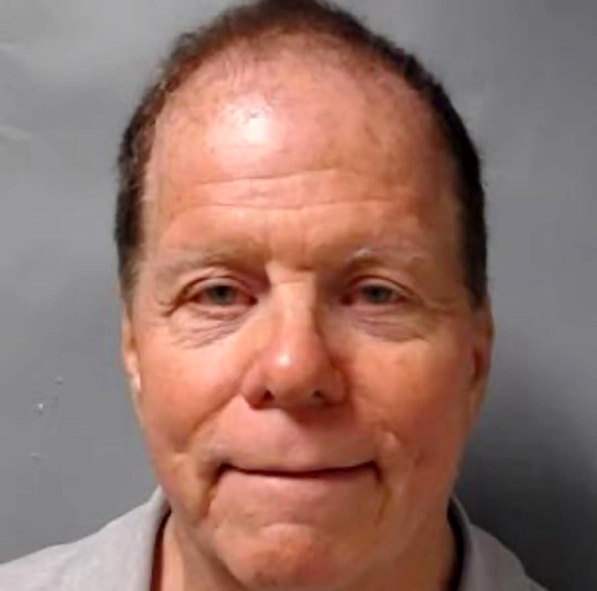 Mugshot of a slightly smiling man with thinning hair.